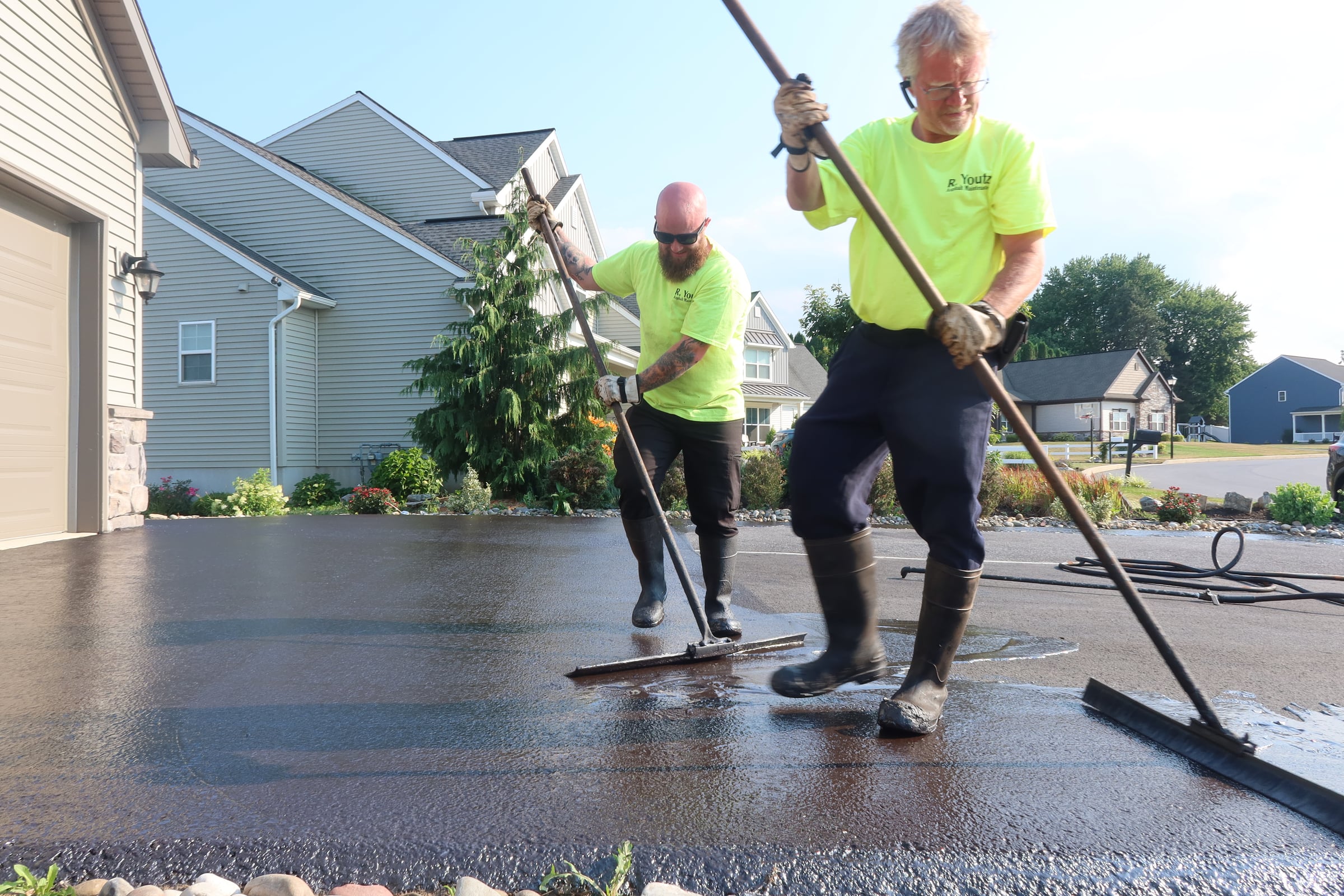 R. Youtz crew brushing fresh driveway sealcoat